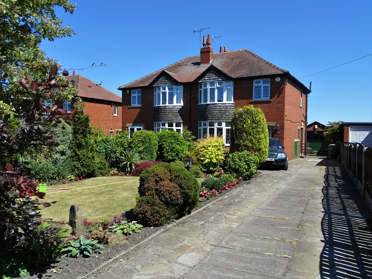 1930s red brick semi-detached house with bay windows, a hipped tiled roof and a neat front garden in Yorkshire