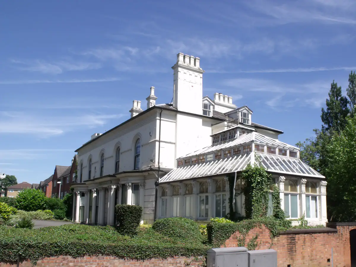 White rendered Victorian villa with a long glass roofed conservatory under a blue sky in Edgbaston, Birmingham