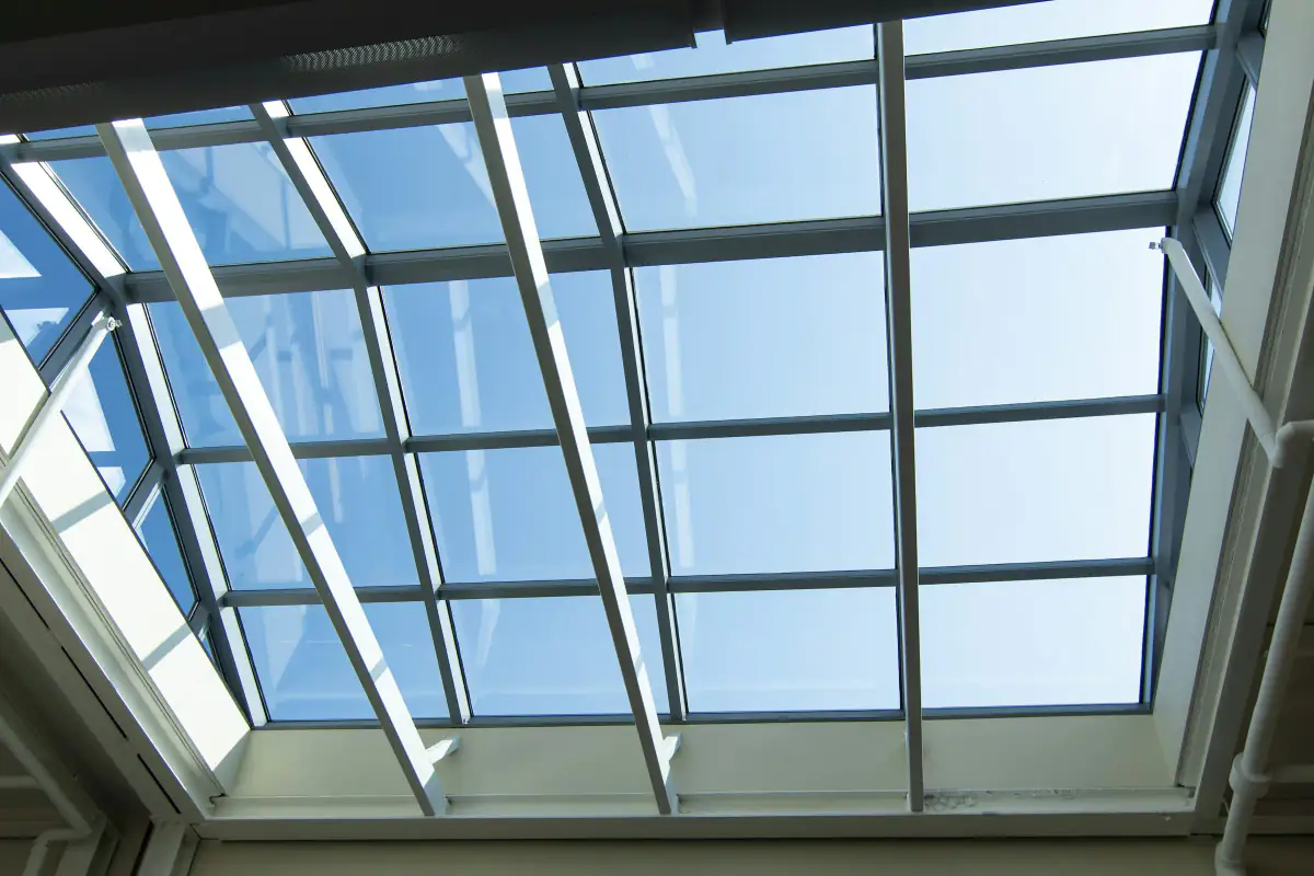 White framed glass roof lantern seen from below against a clear blue sky